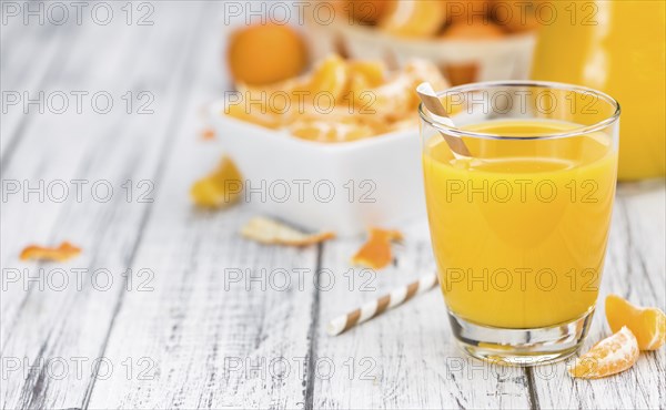 Homemade Tangerine Juice on an old and rustic wooden table (selective focus, close-up shot)