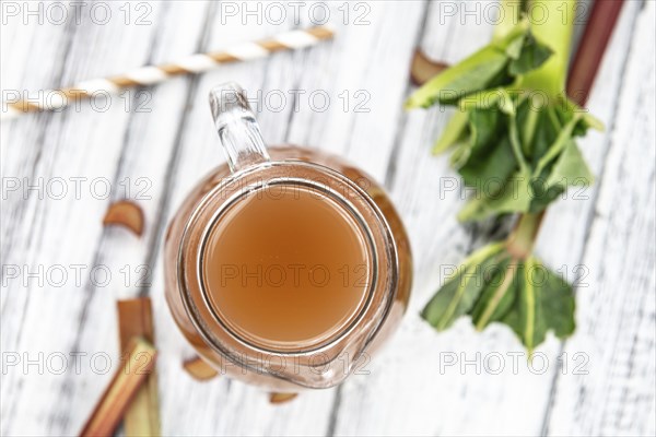 Old wooden table with fresh made Rhubarb Juice as detailed close up shot (selective focus)