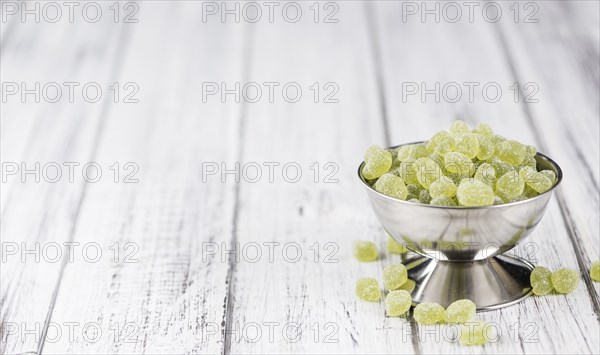 Sour gummy candy (apple taste) on an old wooden table (selective focus)
