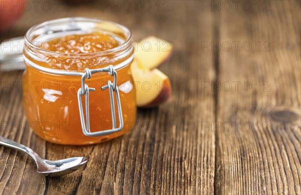 Portion of Peach Jam (close-up shot) on an old wooden table