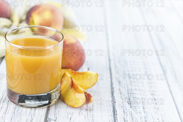 Fresh made Peach juice (detailed close-up shot) on wooden background