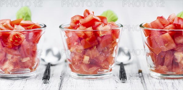 Tomatoes (diced) as high detailed close-up shot on a vintage wooden table (selective focus)