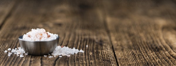 Salt (pink) on an old wooden table as detailed close-up shot (selective focus)