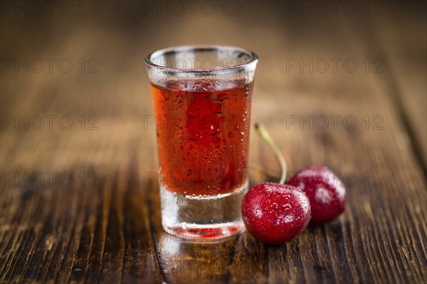 Cherry Liqueur as high detailed close-up shot on a vintage wooden table, selective focus