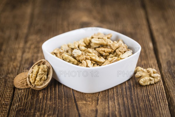 Walnuts (kernels) on an old wooden table as detailed close-up shot (selective focus)