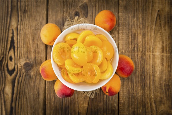 Canned Apricots on rustic wooden background (close-up shot)