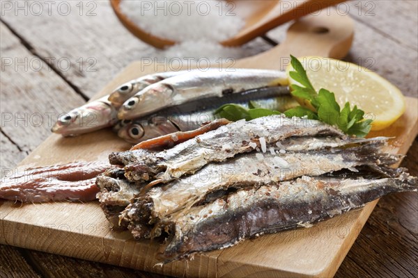 Marinated anchovies with salt and lemon on wooden table