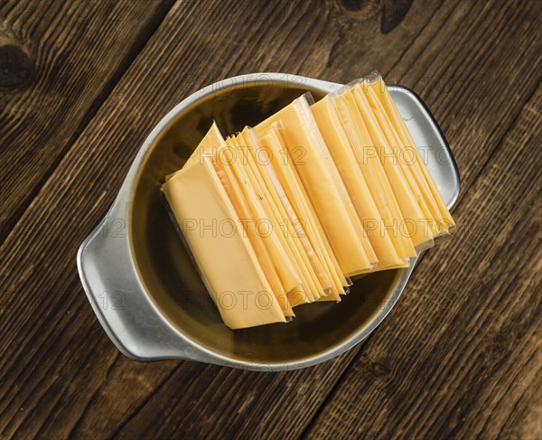 Cheese (sliced) on an old wooden table as detailed close-up shot (selective focus)