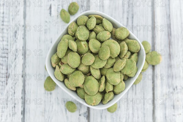 Peanuts (with Wasabi flavor) on an old wooden table as detailed close-up shot (selective focus)