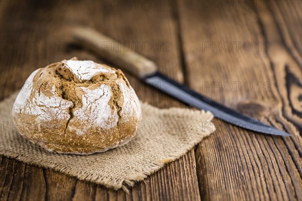 Wholemeal Roll on rustic wooden background (close-up shot)