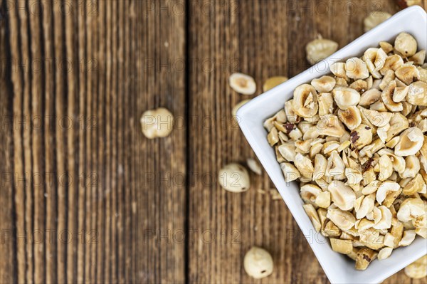Portion of freshly chopped Hazelnuts on an old wooden table as detailed close up shot (selective