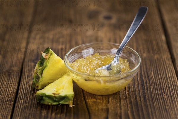 Pineapple Jam as high detailed close-up shot on a vintage wooden table, selective focus