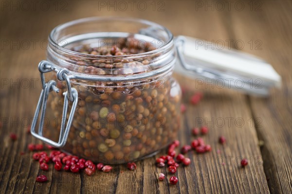 Preserved Pink Peppercorns on a vintage background as detailed close-up shot, selective focus