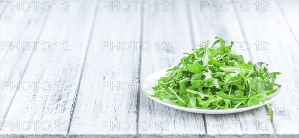 Wooden table with fresh Arugula as detailed close-up shot (selective focus)