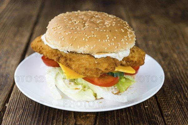Wooden table with a fresh made Fish Burger (close-up shot, selective focus)