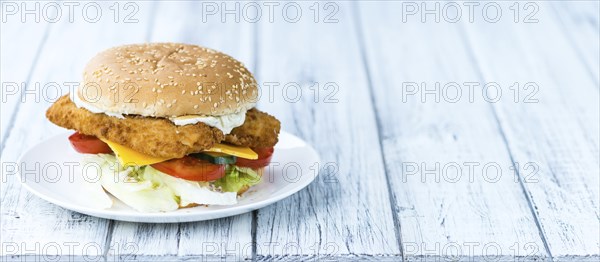 Homemade Fish Burger (close-up shot, selective focus) on a wooden table