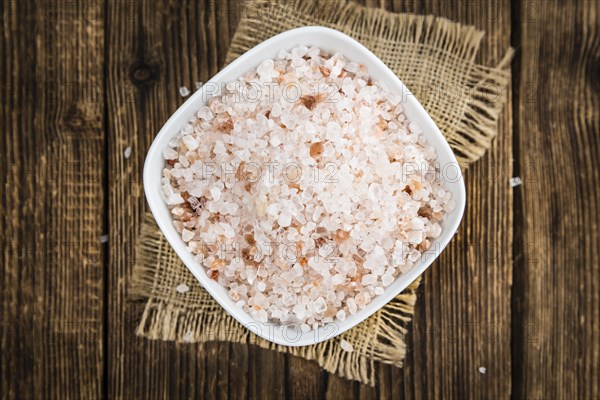 Salt (pink) on an old wooden table as detailed close-up shot (selective focus)