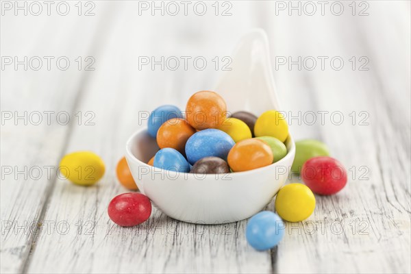 Cocolate coated Peanuts on an old wooden table as detailed close-up shot (selective focus)