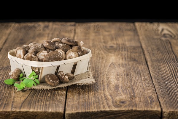 Raw Shiitake mushrooms as high detailed close-up shot on a vintage wooden table, selective focus