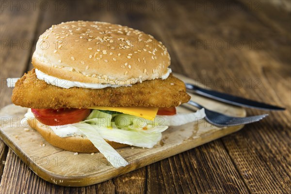 Fish Burger on wooden background (close-up shot, selective focus)