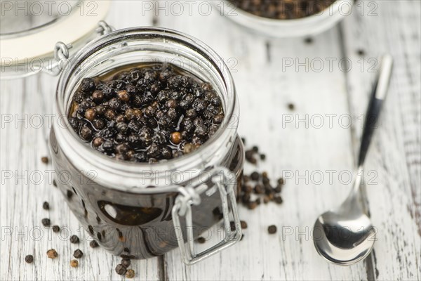 Preserved black Peppercorns on wooden background, selective focus, close-up shot