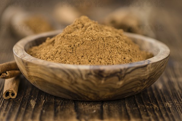 Cinnamon Powder as high detailed close-up shot on a vintage wooden table (selective focus)