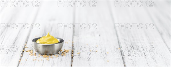 Fresh made Mustard on a vintage background (close-up shot)