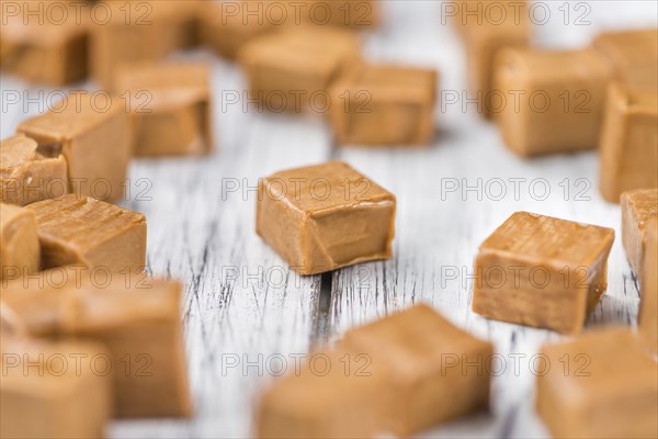 Caramel pieces as high detailed close-up shot on a vintage wooden table (selective focus)