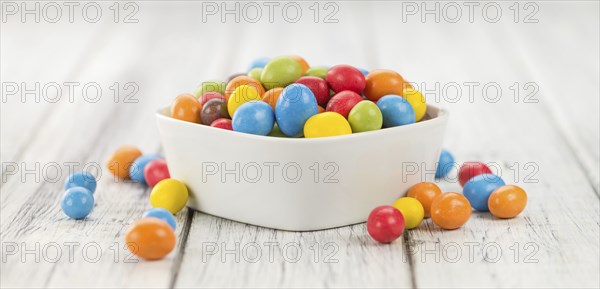 Cocolate coated Peanuts on rustic wooden background (close-up shot)