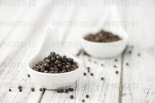 Preserved black Peppercorns on wooden background, selective focus, close-up shot