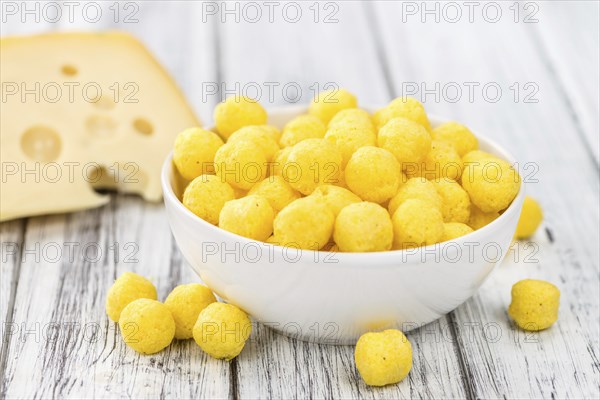 Cheese Balls on an old wooden table as detailed close-up shot (selective focus)