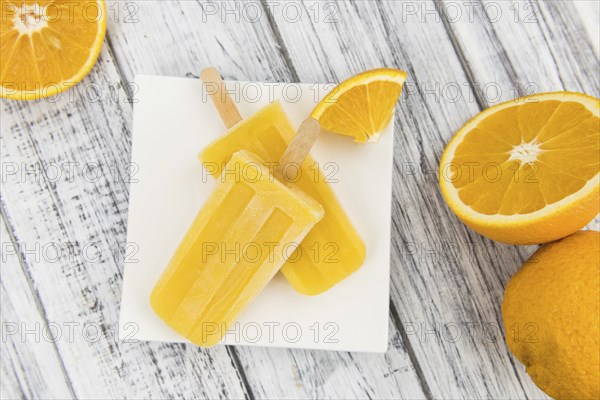 Orange Popsicles (selective focus, close-up shot) on a vintage background