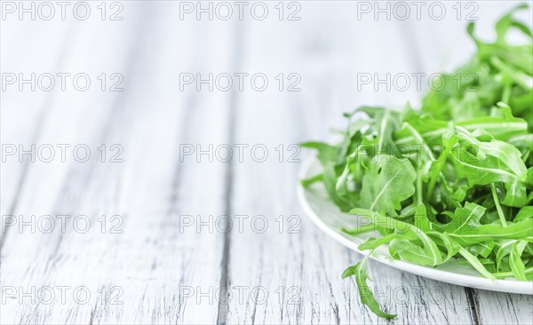 Wooden table with fresh Arugula as detailed close-up shot (selective focus)