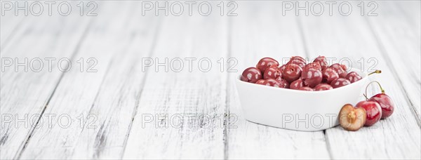 Preserved Cherries on an old wooden table as detailed close-up shot, selective focus