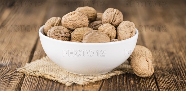 Walnuts on rustic wooden background (close-up shot)