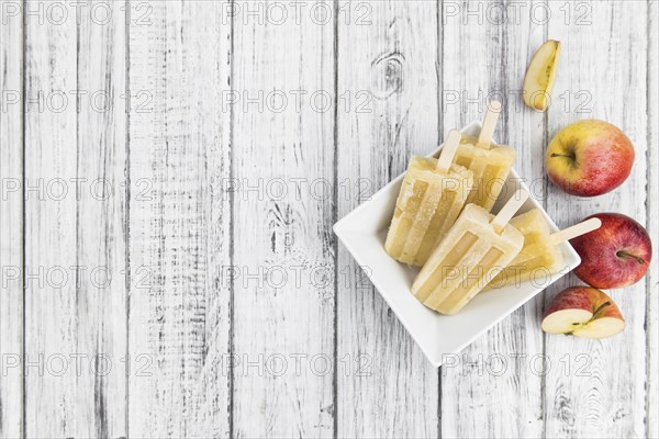 Portion of homemade Apple Popsicles (selective focus, close-up shot) on a vintage background
