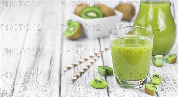 Wooden table with fresh made Kiwi Smoothie (close-up shot, selective focus)