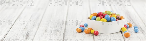 Cocolate coated Peanuts on an old wooden table as detailed close-up shot (selective focus)