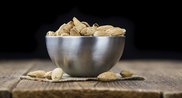 Roasted and salted Almonds (with shell) on a vintage background (close-up shot)