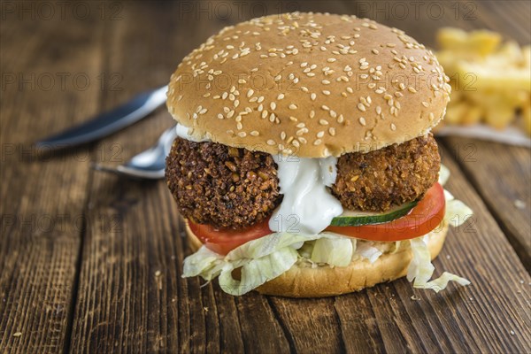 Vegetarian Falafel Burger on an old wooden table (close-up shot, selective focus)