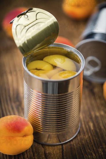 Canned Apricots on rustic wooden background (close-up shot)