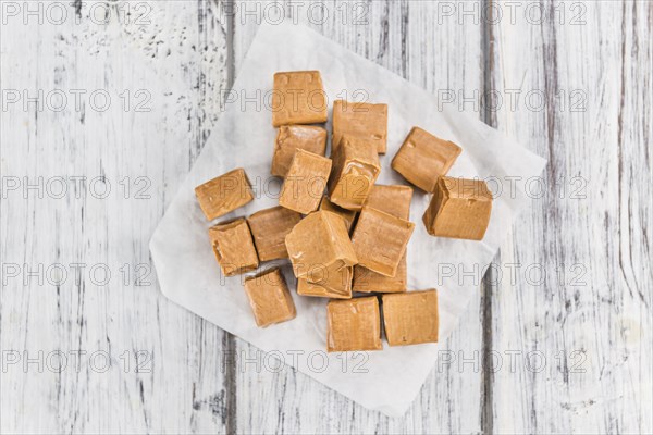 Portion of homemade Caramel on wooden background (selective focus, close-up shot)