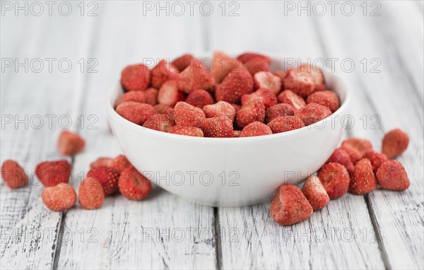 Strawberries (dried) as high detailed close-up shot on a vintage wooden table, selective focus