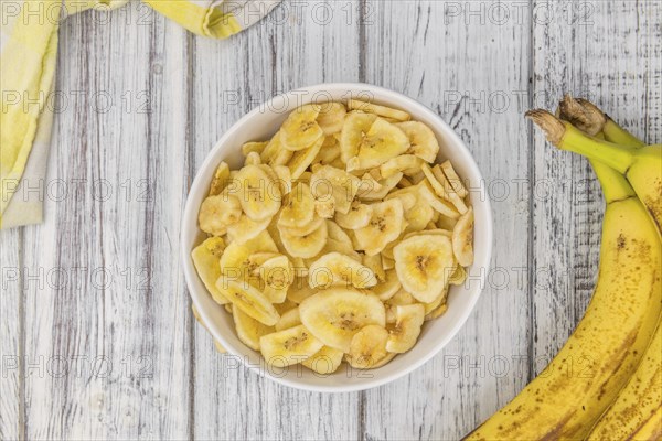Fresh made Dried Banana Chips on an old and rustic wooden table, selective focus, close-up shot
