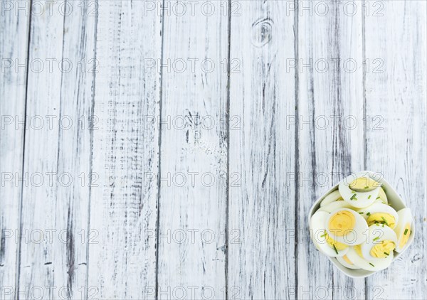 Halved Eggs on wooden background (close-up shot, selective focus)