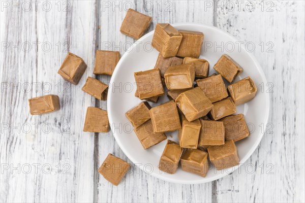Portion of homemade Caramel on wooden background (selective focus, close-up shot)