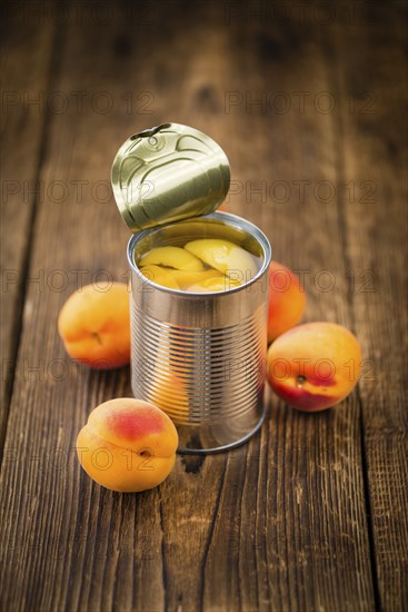 Canned Apricots on an old wooden table as detailed close-up shot (selective focus)
