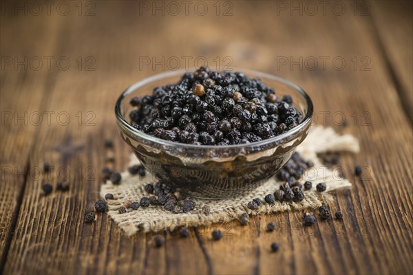 Preserved black Peppercorns on a wooden table as close-up shot