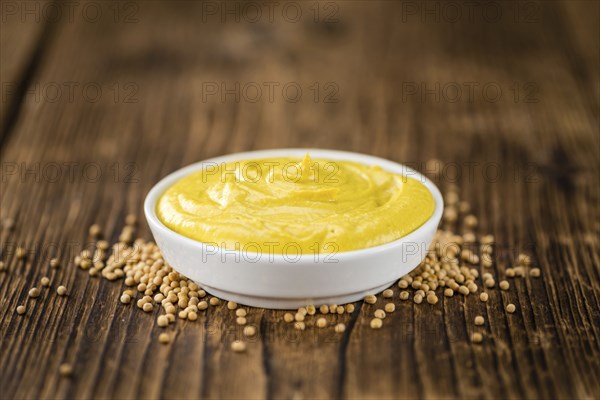 Portion of homemade Mustard on wooden background (selective focus, close-up shot)
