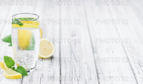 Lemonade (with Balm) as high detailed close-up shot on a vintage wooden table (selective focus)